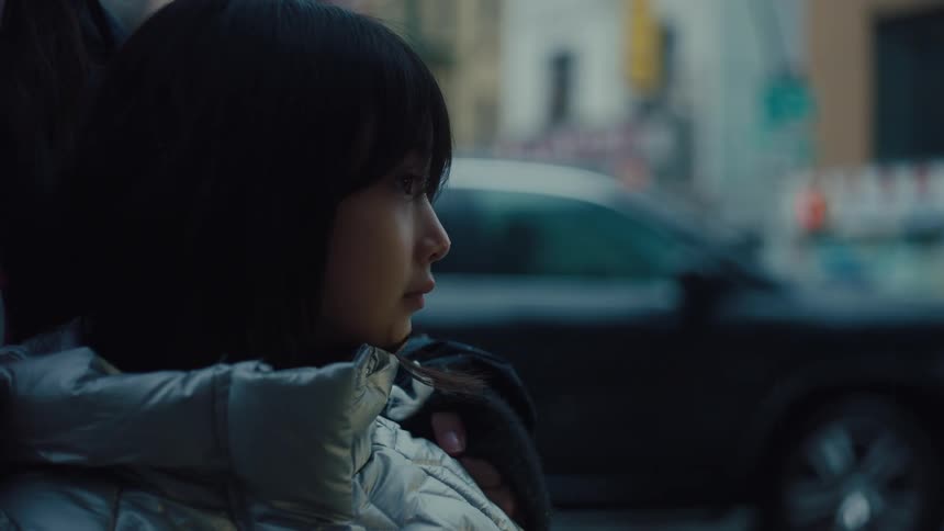 Girl in jacket accompanied by a person in an urban outdoor environment