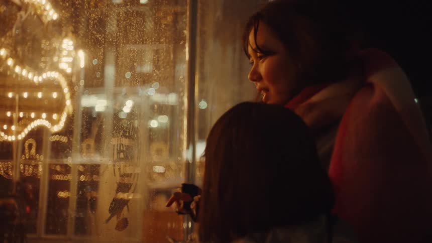A woman drawing with her finger on a glass surface while a child watches and draws too