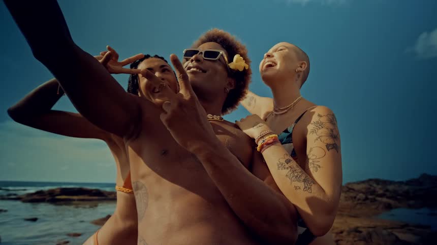 Man and two women in a beach setting taking a selfie