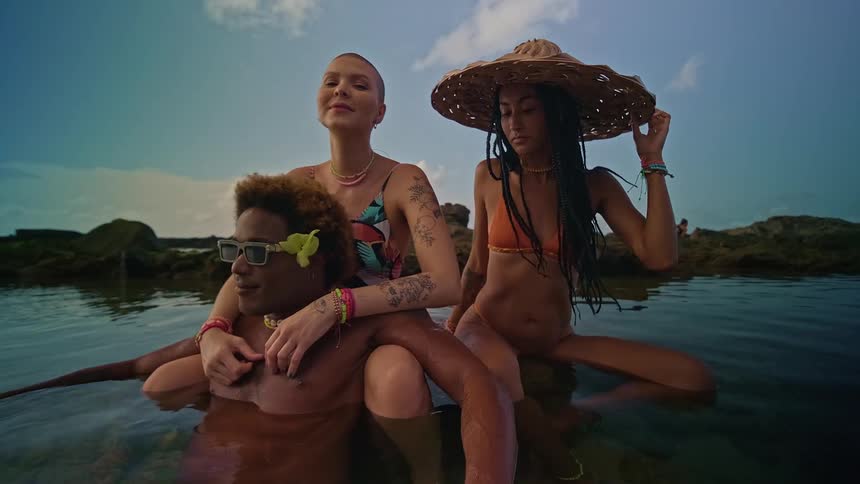 Three friends sitting on rocks in the middle of the sea