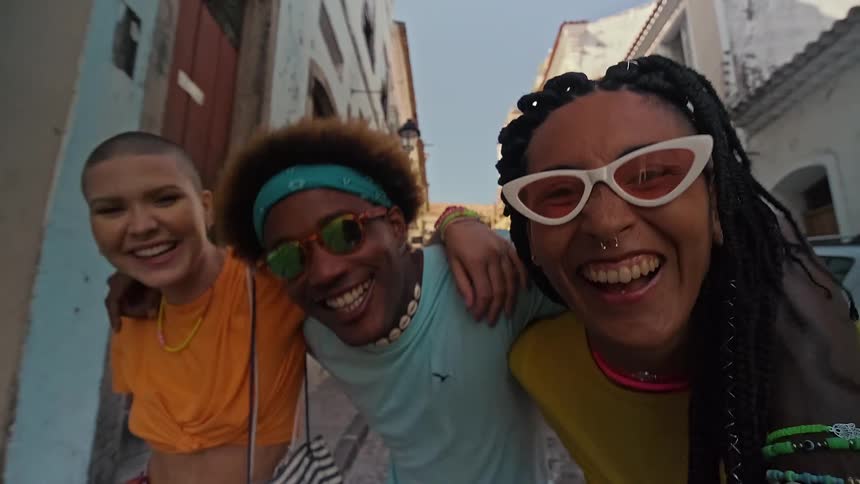 Three people smile while running down the cobblestone road