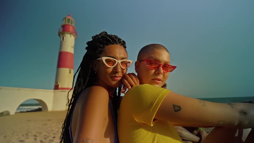 Two women sit on the beach together