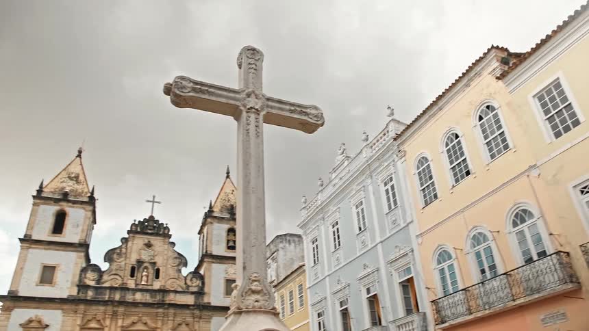Monument of a cross in a square in front of a classical church