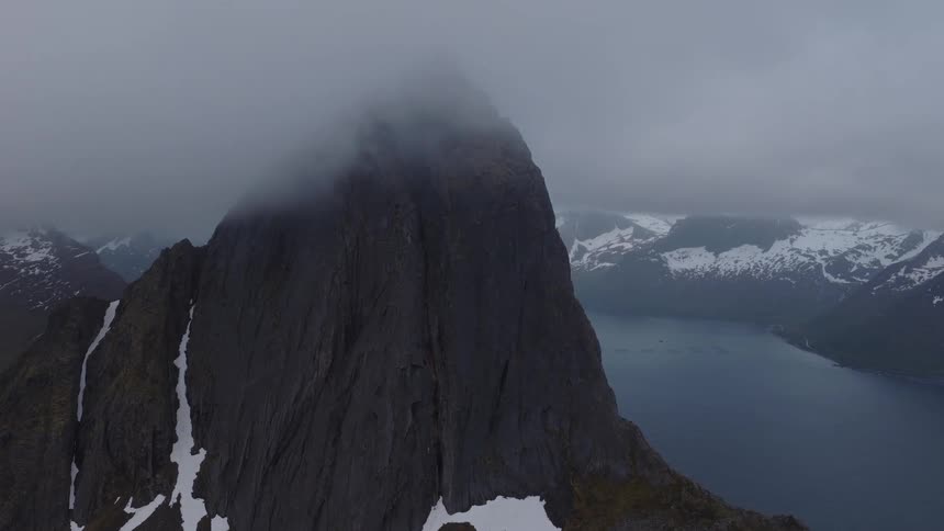 Aerial view of sea surrounded by snowy mountains on a cloudy day
