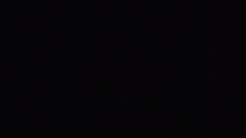 Woman stands silhouetted in a room lit by the light from a large wall sized screen