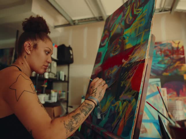 Woman sitting in front of a canvas painting