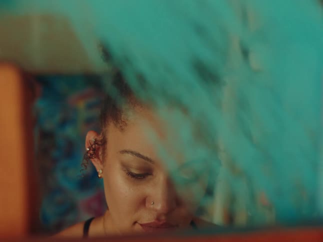 Woman concentrated in an interior space painting a canvas with light blue paint