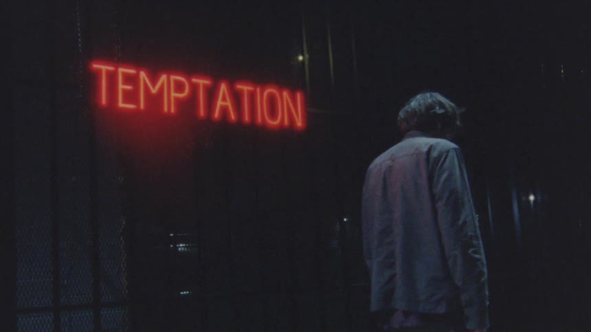 A man walks past the neon sign on the building