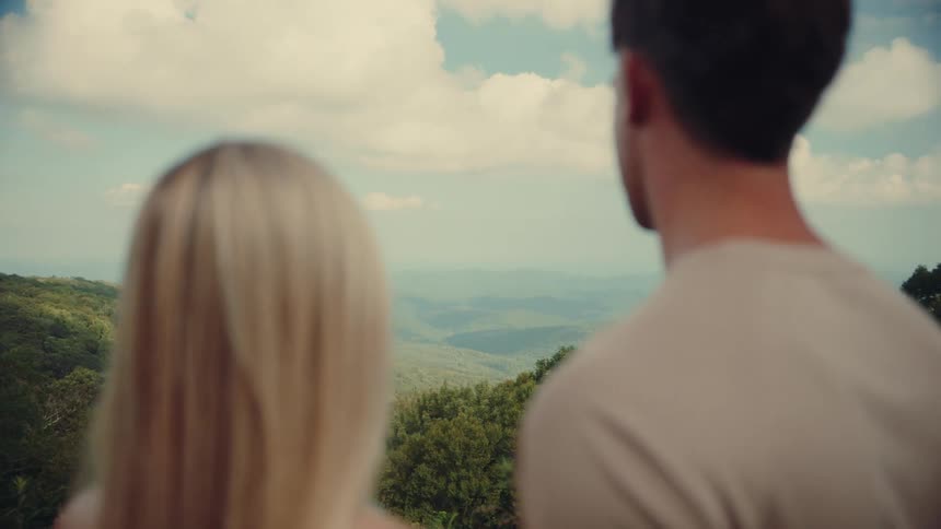 Man and woman stand on a mountain enjoying the view