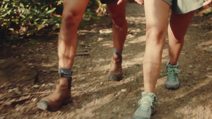 The legs of a couple walking through nature on a hiking trail
