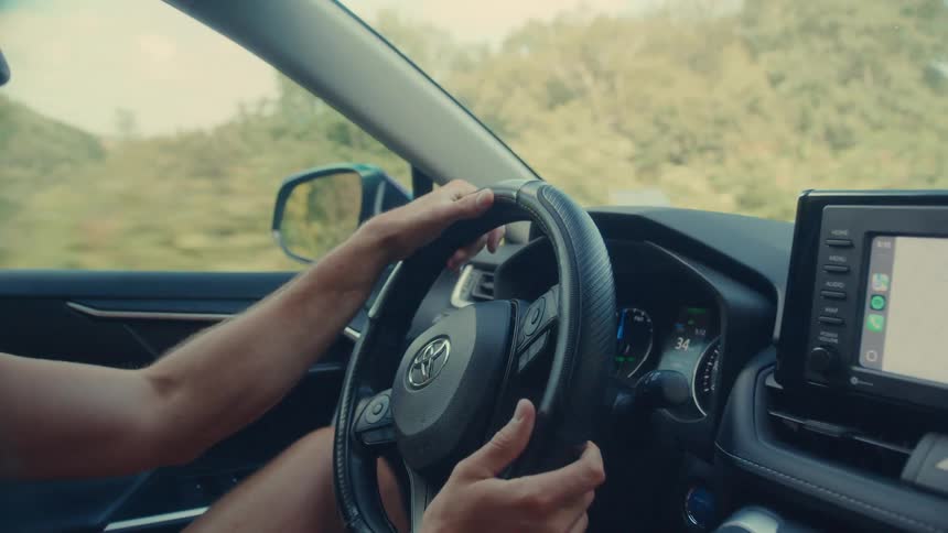 Pair of hands of a man on the steering wheel driving a car