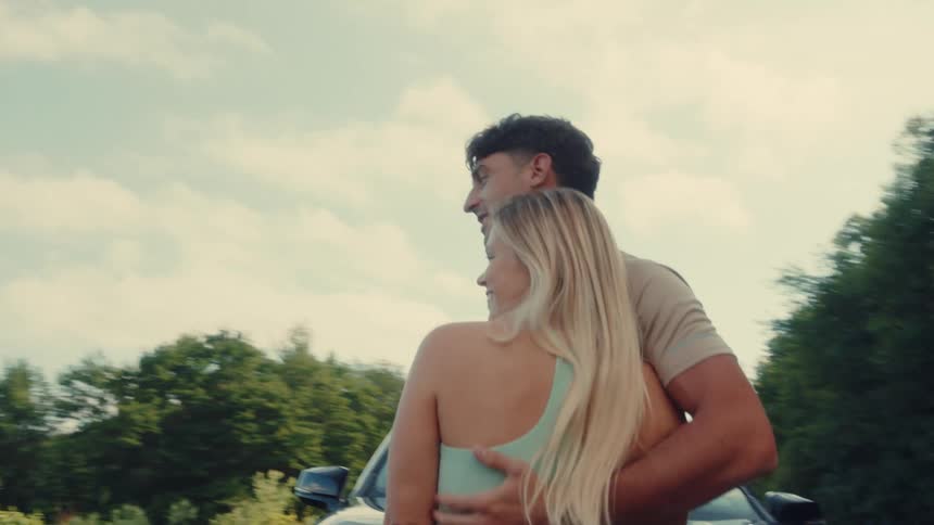 Couple stepping out of a black suv and embracing overlooking a mountainous landscape