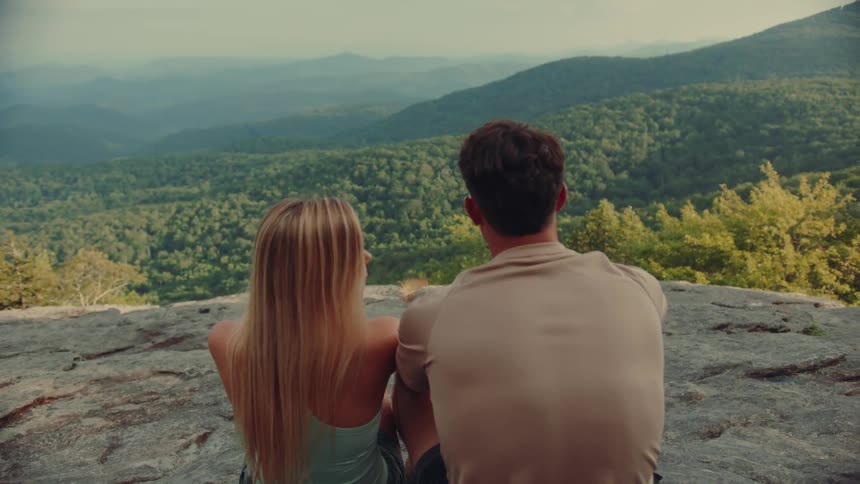 Couple sits at a lookout point watching the foggy mountains on a summer day