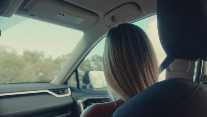 The woman is riding in the passenger seat of the car