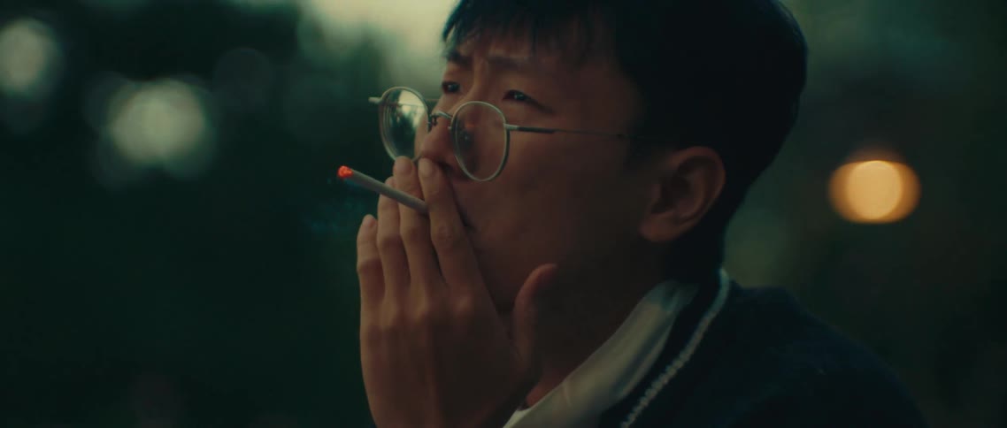 Young man with glasses lighting and smoking a cigarette