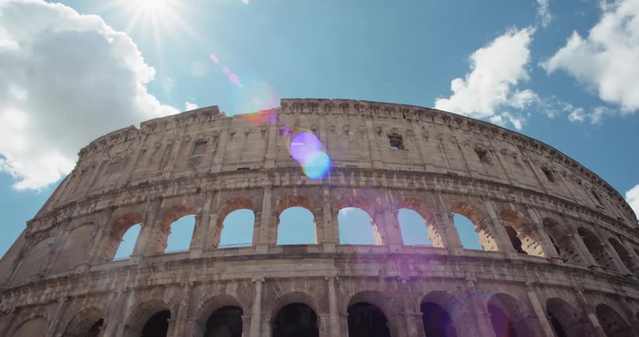 The ancient roman colosseum stands grandly under a blue sky with scattered clouds