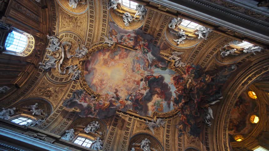 An ornate cathedral ceiling features intricate gold details and a dramatic fresco filled with angels and divine figures