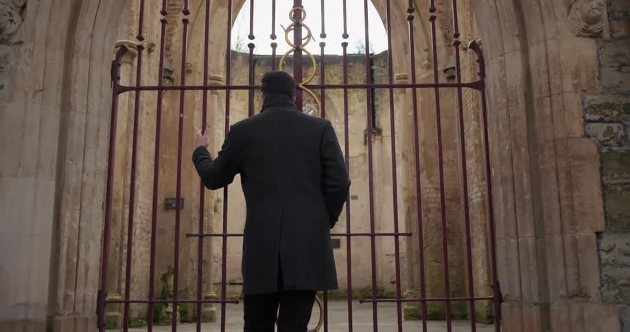 A man stands outside a closed gate