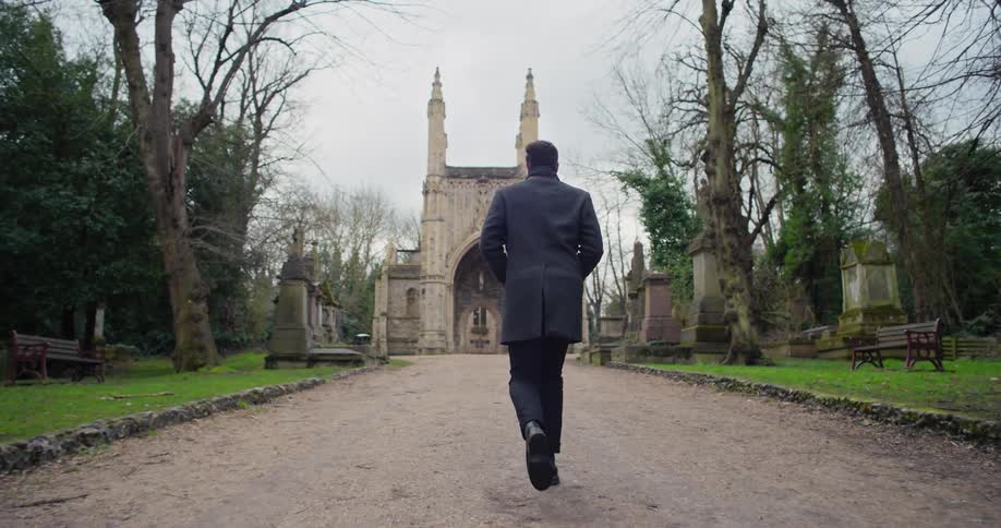 Man walking through a cemetery towards a gothic church