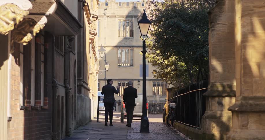 Two men chat while walking down a sidewalk