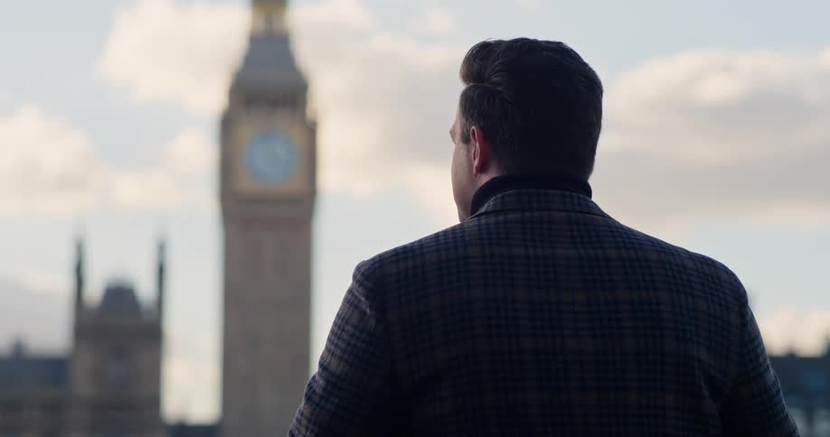 The man is looking over at the clock tower