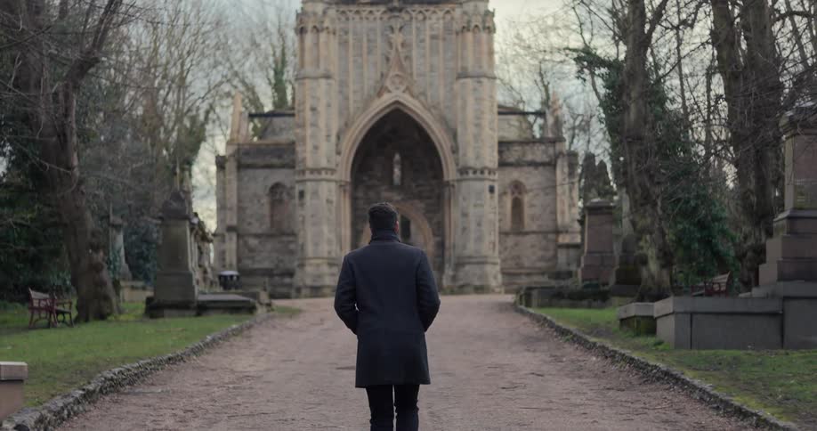 A young man walks down a road entrance that leads to a castle gate during daytime