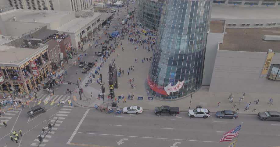 A drone circles bridgestone arena at sunset capturing its sleek design and the lively crowd gathered outside
