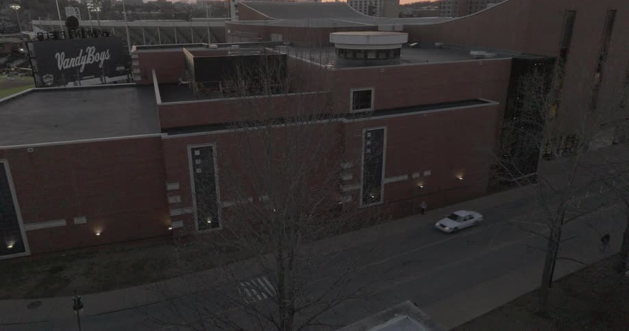 The back side of memorial gymnasium stands quiet at dusk with a billboard reading vandyboys above the nearby field
