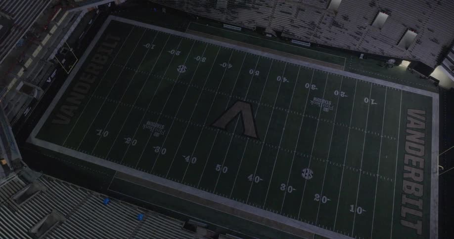 An empty american football stadium is seen from an aerial view with the vanderbilt logo clearly visible at the center of the field