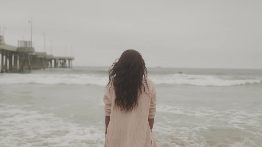A woman at the edge of the beach watching the sea