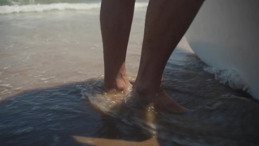 Person feet at the shoreline with water covering the ankles