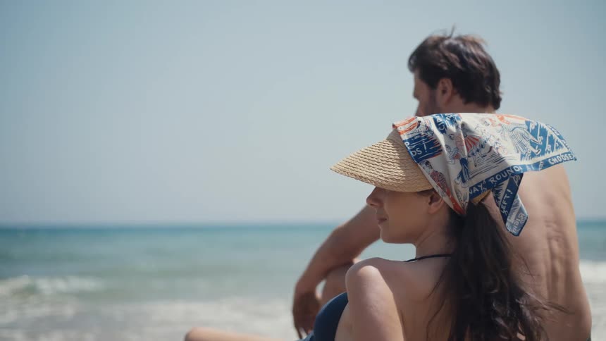 Couple sitting by the sea looking at the horizon