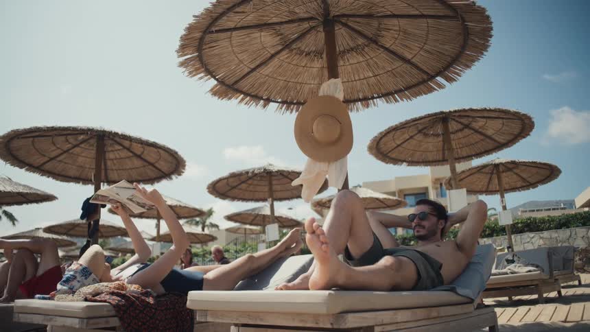 People enjoy themselves while lying on lounge chairs at a resort