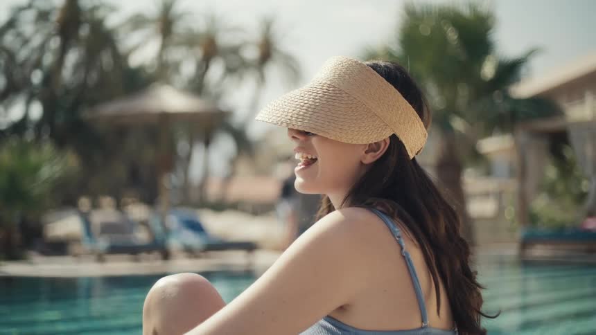 Smiling woman relaxes by the pool engaged in conversation