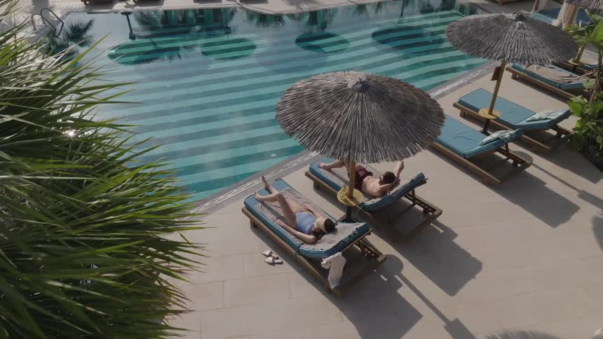 Two people are relaxing by the pool
