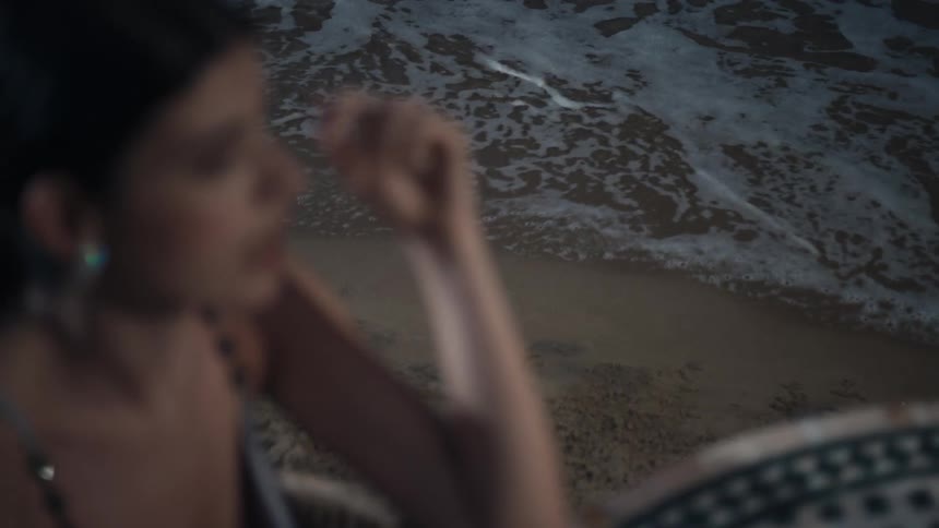 A woman is talking while sitting on the beach