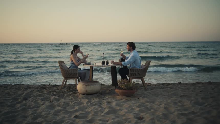 A couple have drinks on the beach