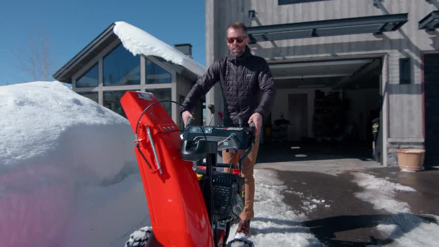 The man starts up his snow blower and pushes it forward