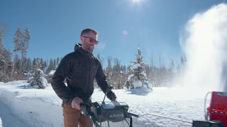 A man uses a snowblower