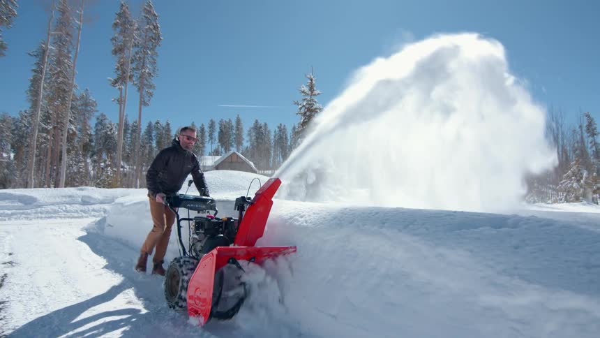A man uses a snowblower