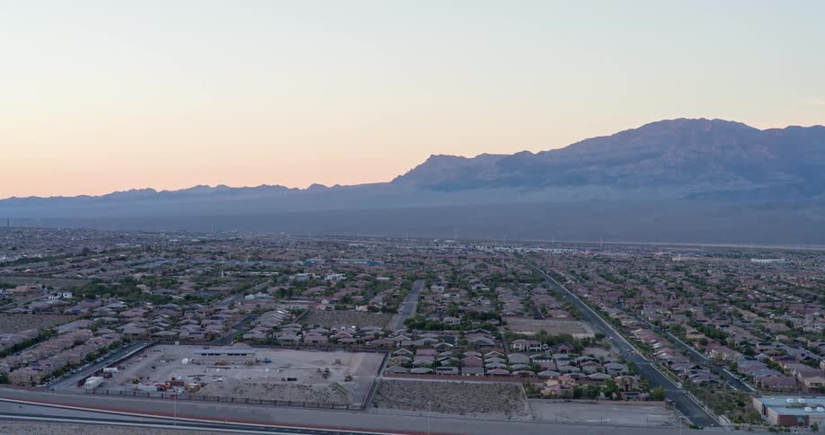 A suburban neighborhood stretches toward distant mountains at dusk