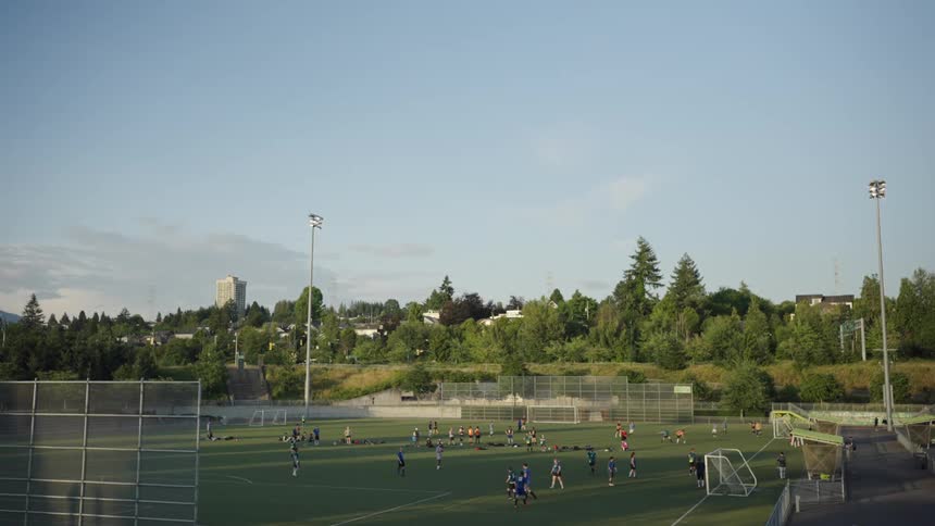 Soccer players on a field surrounded by greenery during daytime