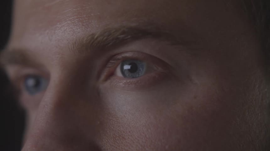 A closeup of a mans intense blue eye captures fine facial details and focused expression
