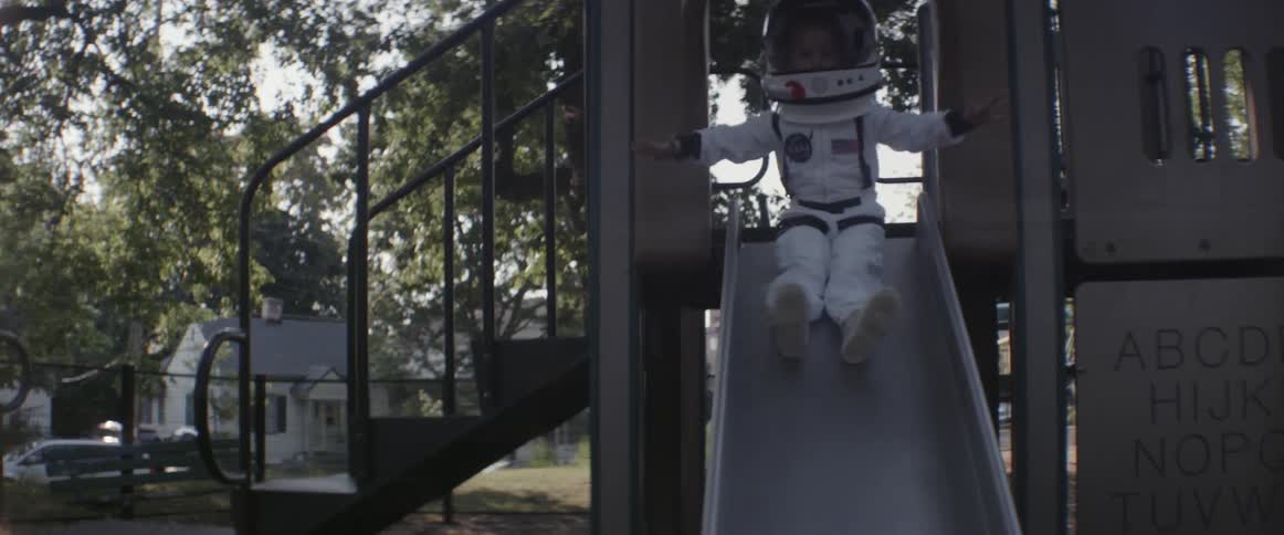 A girl wearing a space suit slides down a slide