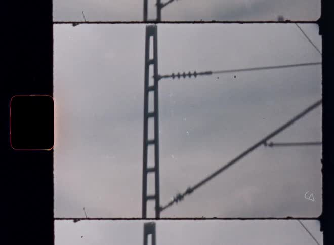 The video shows a quick closeup of a power line against a gray cloudy sky the footage has a vintage retro feel with a super 8 film border