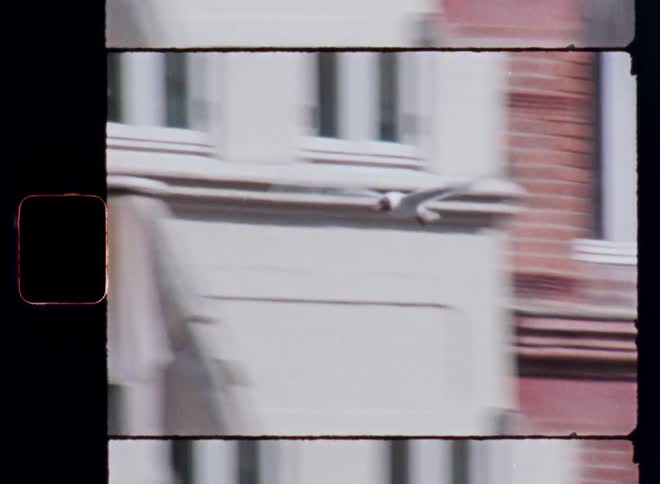 A vintagestyle frame captures a blurry view of red brick buildings and a closed patio umbrella as a large bird flies