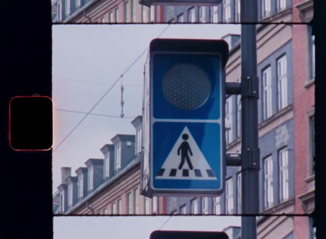A pedestrian crossing sign and signal on a pole in the city