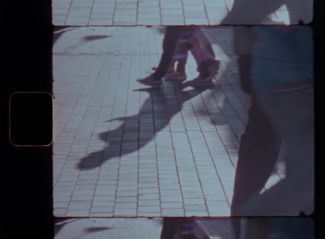 Shadows and legs of people walking on a stone pavement