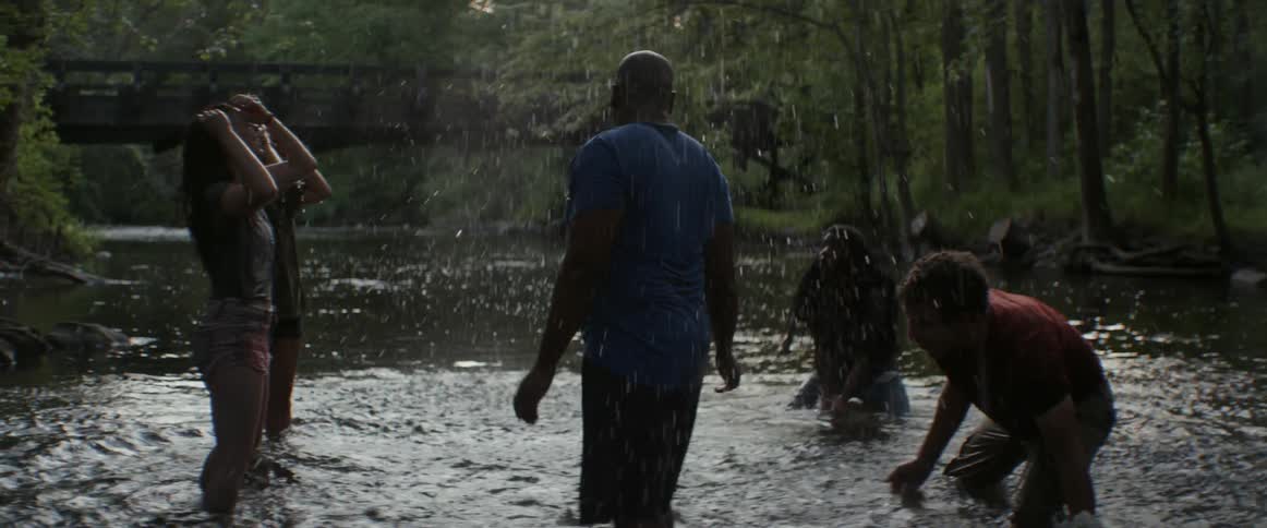 A group of people splash in a shallow river