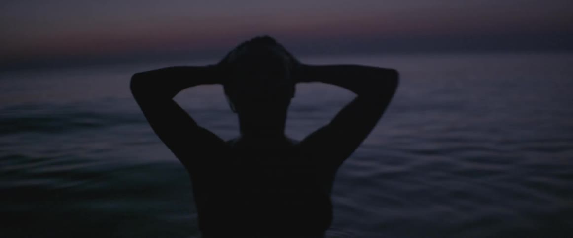 A woman washes her hair in the ocean
